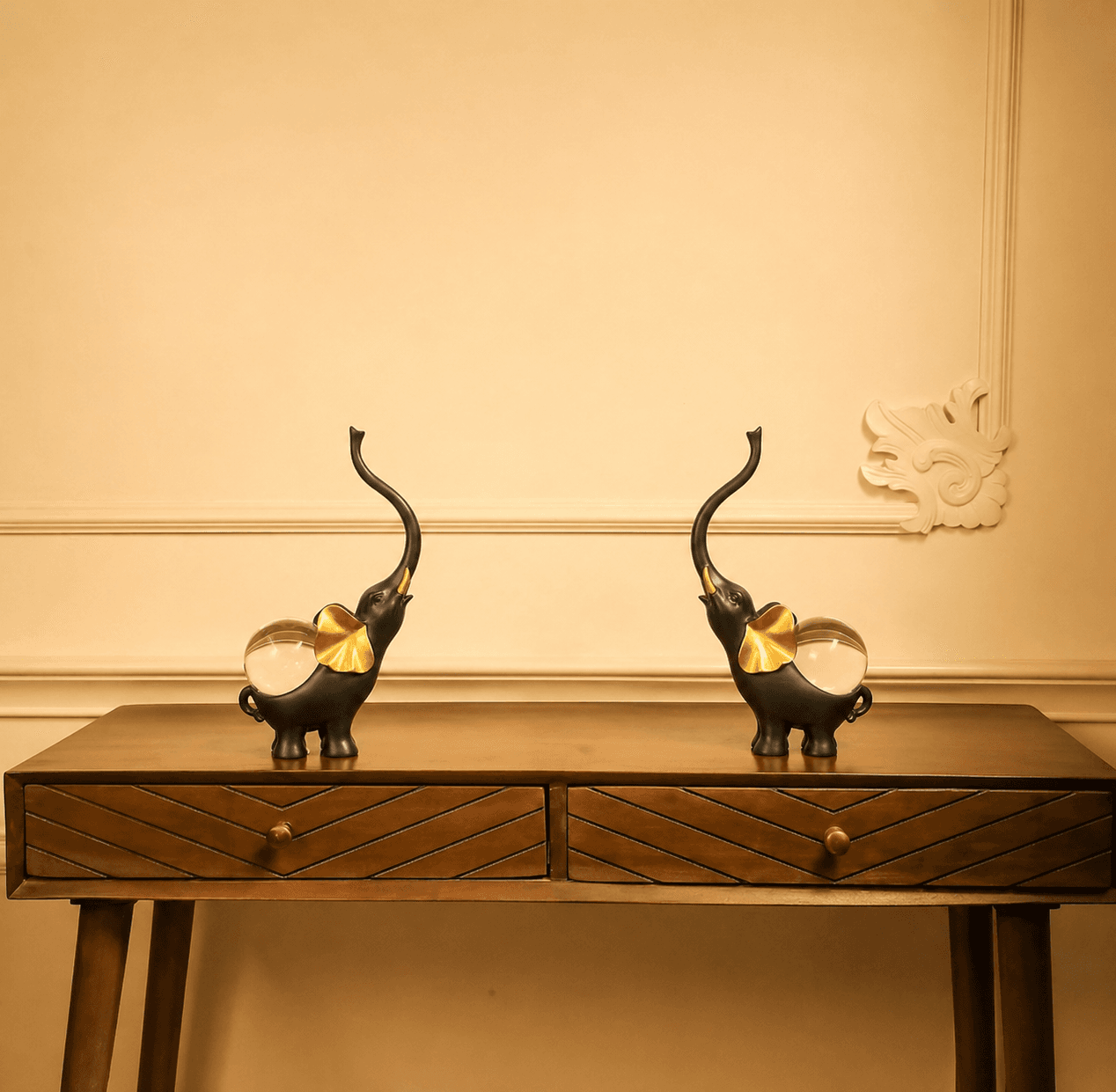 Pair of black elephant statues with golden ears and clear crystal balls on their backs, displayed on a wooden entryway console table preview 3